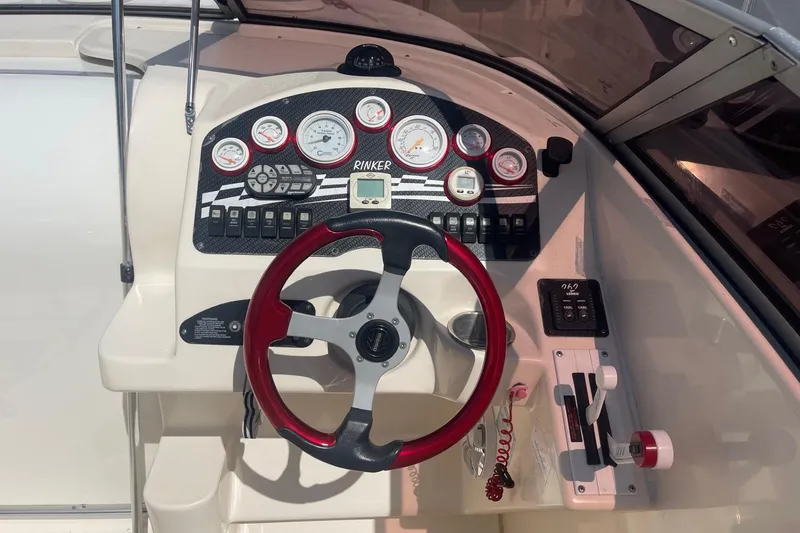 Slide: The Image of 2001 Rinker 262 Captiva boat dashboard with gauges and red steering wheel. - 9