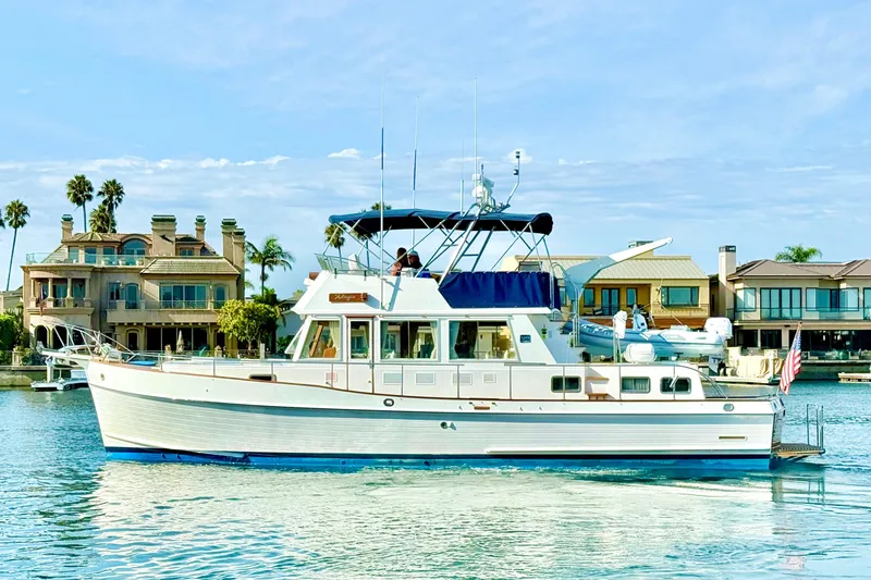 Slide: The Image of 2001 Grand Banks 46 Classic yacht cruising near waterfront homes. - 3