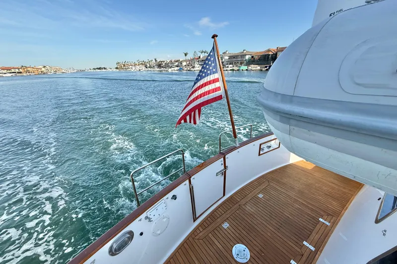 Slide: The Image of Grand Banks 46 Classic yacht, 2001, cruising with American flag, wooden deck, coastal view. - 40