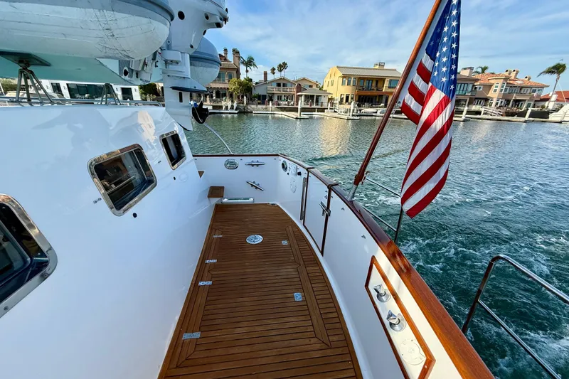 Slide: The Image of Grand Banks 46 Classic yacht deck, 2001 model, with American flag, docked near waterfront homes. - 43