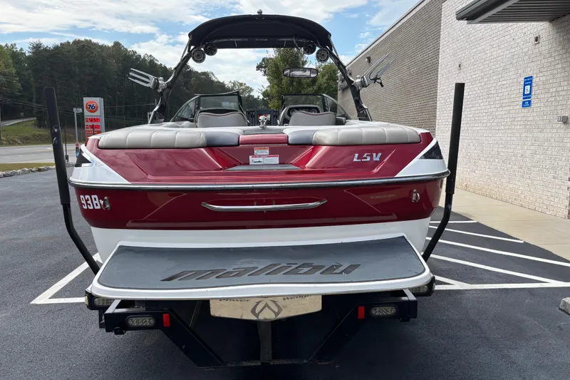 Slide: The Image of 2008 Malibu Wakesetter 23 LSV boat, red and white, parked near a building. - 3