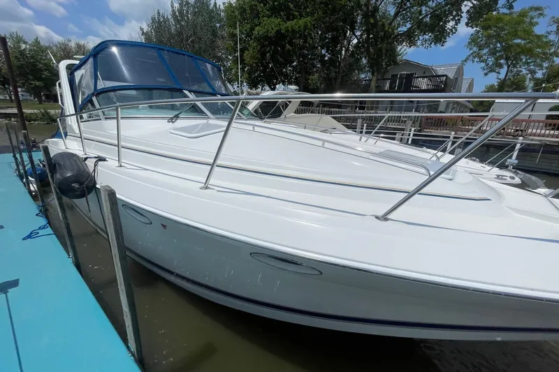 Slide: The Image of 1999 Formula 31 Performance Cruiser docked beside Crestliner boat, surrounded by trees and houses. - 0