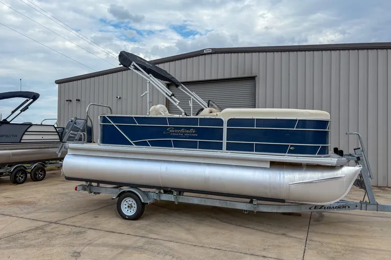 Slide: The Image of 2016 Godfrey Sweetwater 2086 C pontoon boat on trailer, parked outside a metal building. - 3