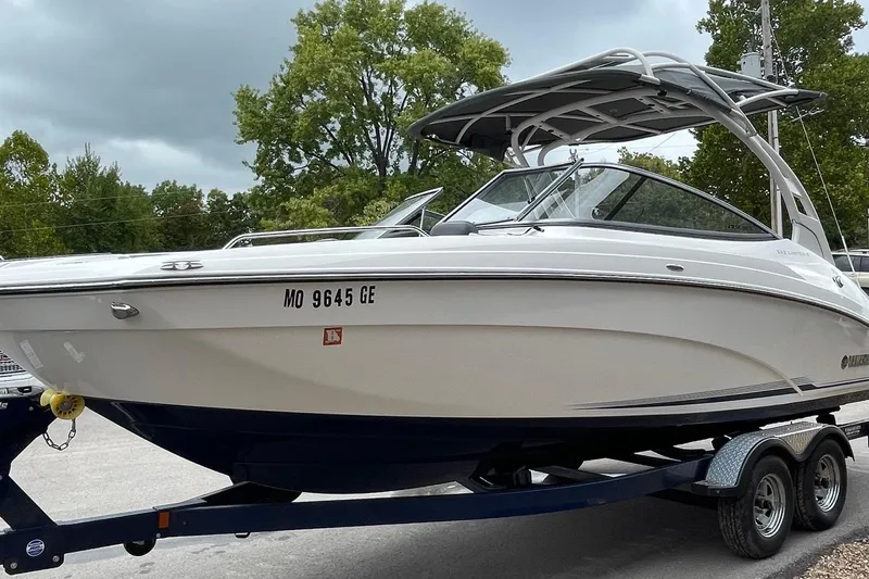Slide: The Image of 2017 Yamaha 242 boat on trailer, parked outdoors with trees in background. - 3