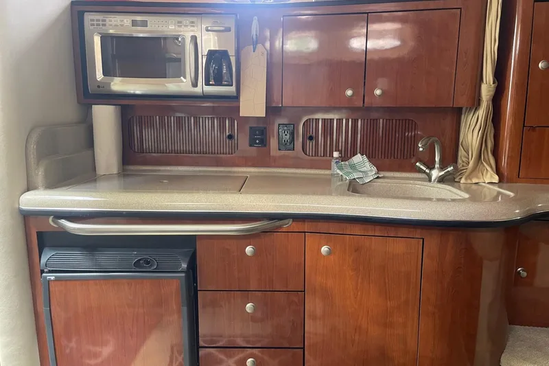 Slide: The Image of 2007 Sea Ray 320 Sundancer kitchen with microwave, sink, and wooden cabinetry. - 27