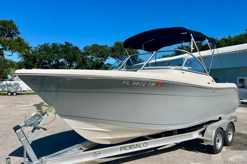 The Image of 2023 Cobia 200 DC boat on trailer, parked outdoors with blue sky background. - 0