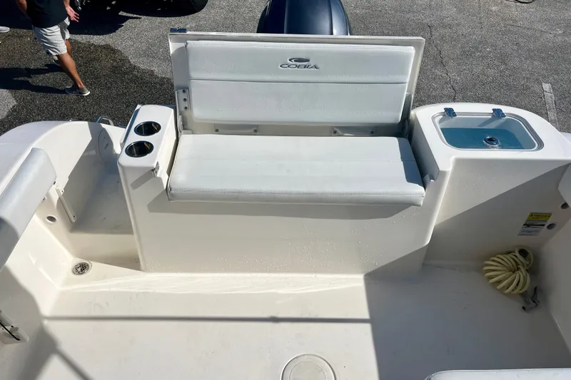 Slide: The Image of 2023 Cobia 200 DC boat interior with seating, cup holders, and storage compartment. - 11