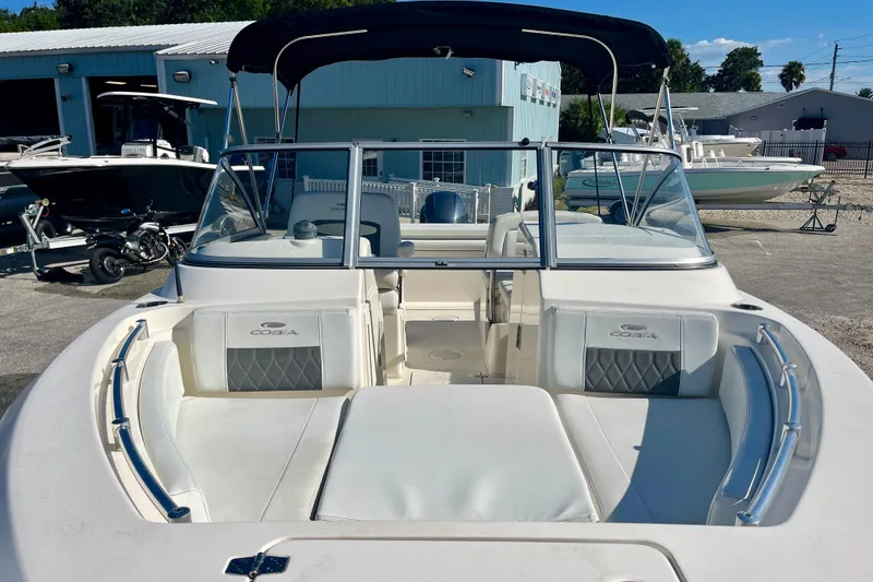Slide: The Image of 2023 Cobia 200 DC boat with seating, windshield, and canopy in a marina setting. - 4
