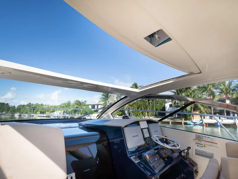 Slide: The Image of 2014 Pursuit SC 365i Sport Coupe helm with open roof, showcasing marina view. - 10