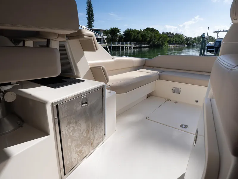 Slide: The Image of 2014 Pursuit SC 365i Sport Coupe interior with seating and storage, docked by calm waters. - 12