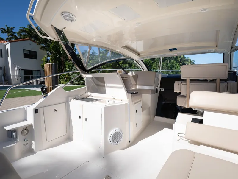 Slide: The Image of 2014 Pursuit SC 365i Sport Coupe interior with seating and helm, docked near modern home. - 4