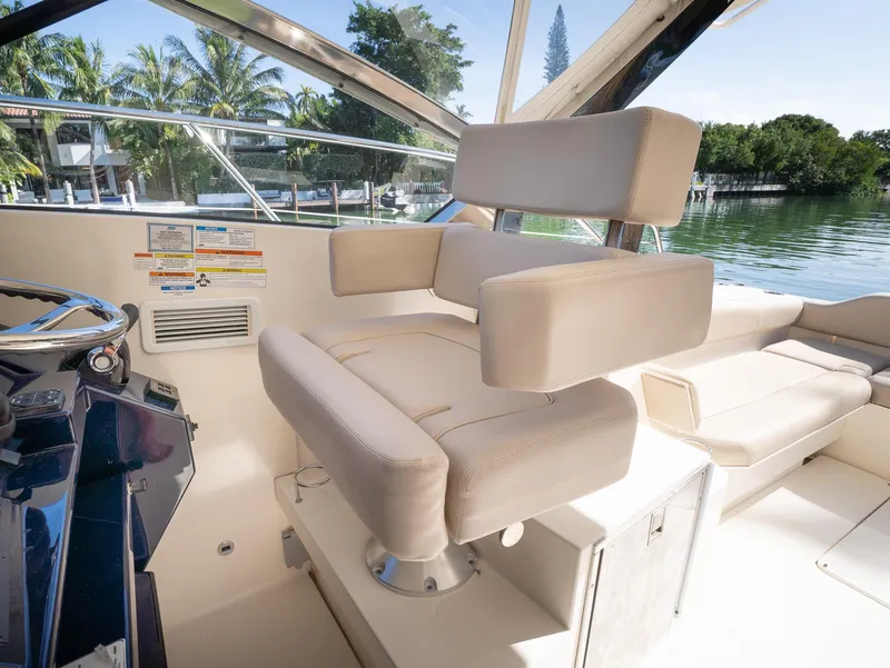 Slide: The Image of Captain's chair on 2014 Pursuit SC 365i Sport Coupe, overlooking serene waters and lush greenery. - 8