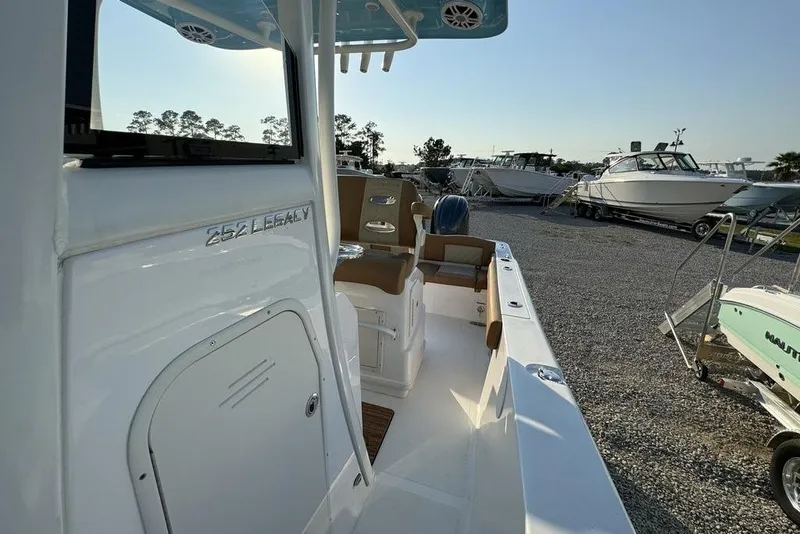 Slide: The Image of 2024 NauticStar 252 Legacy boat, sleek design, docked among other boats, sunny day. - 17
