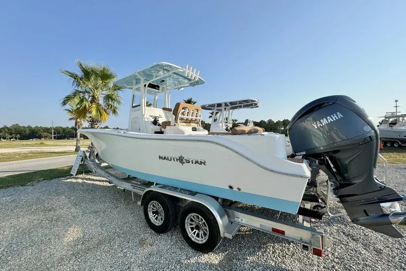 Slide: The Image of 2024 NauticStar 252 Legacy boat on trailer with Yamaha engine, parked outdoors. - 2