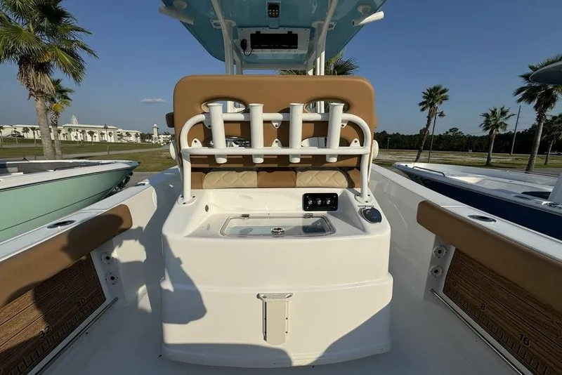 Slide: The Image of 2024 NauticStar 252 Legacy boat interior with rod holders and seating, surrounded by palm trees. - 25