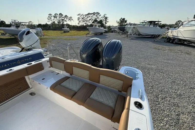 Slide: The Image of 2024 NauticStar 252 Legacy boat with dual engines, parked on gravel lot. - 27