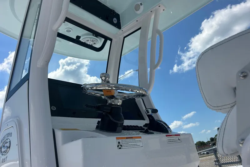 Slide: The Image of 2025 Sportsman Masters 227 Bay Boat helm with chrome steering wheel under blue sky. - 21