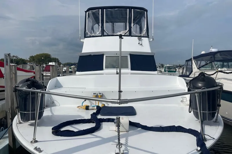 Slide: The Image of 1985 Marinette DC 39 boat docked at marina, featuring spacious deck and protective railings. - 3