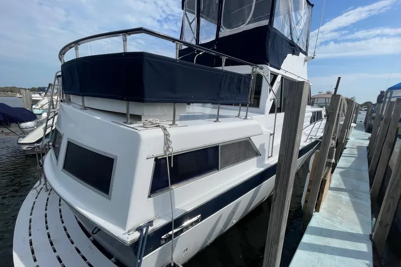 Slide: The Image of 1985 Marinette DC 39 boat docked, featuring a sleek white and blue design under a clear sky. - 4