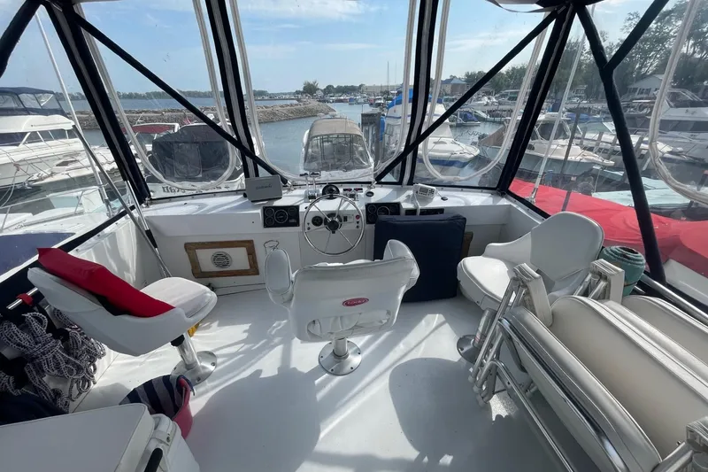 Slide: The Image of Interior of 1985 Marinette DC 39 boat with steering wheel and seating, docked at marina. - 7