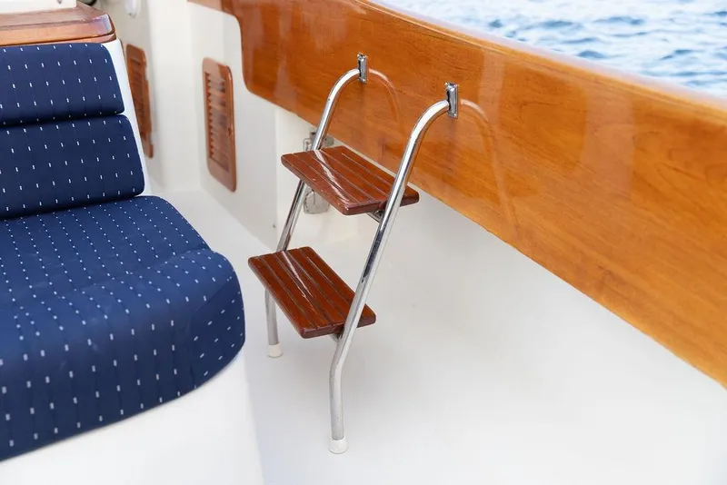 Slide: The Image of 2004 Hinckley Picnic Boat EP interior with wooden ladder and blue cushioned seating. - 10
