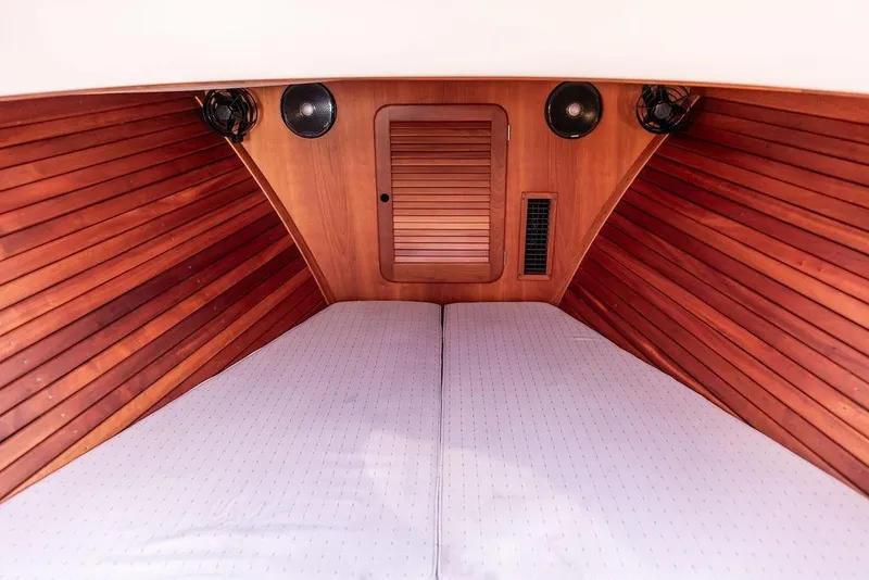 Slide: The Image of 2004 Hinckley Picnic Boat EP interior cabin with wooden paneling and cozy bedding. - 20