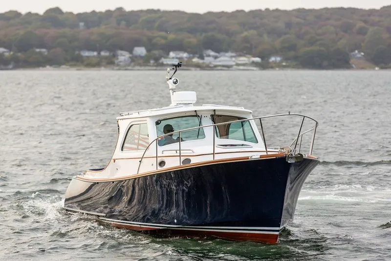 Slide: The Image of 2004 Hinckley Picnic Boat EP cruising on a calm lake with wooded shoreline. - 4