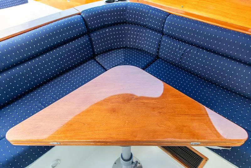 Slide: The Image of 2004 Hinckley Picnic Boat EP interior with blue cushioned seating and wooden table. - 11