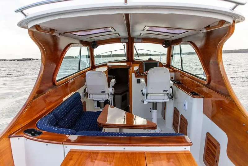 Slide: The Image of 2004 Hinckley Picnic Boat EP interior with polished wood and blue seating on the water. - 12