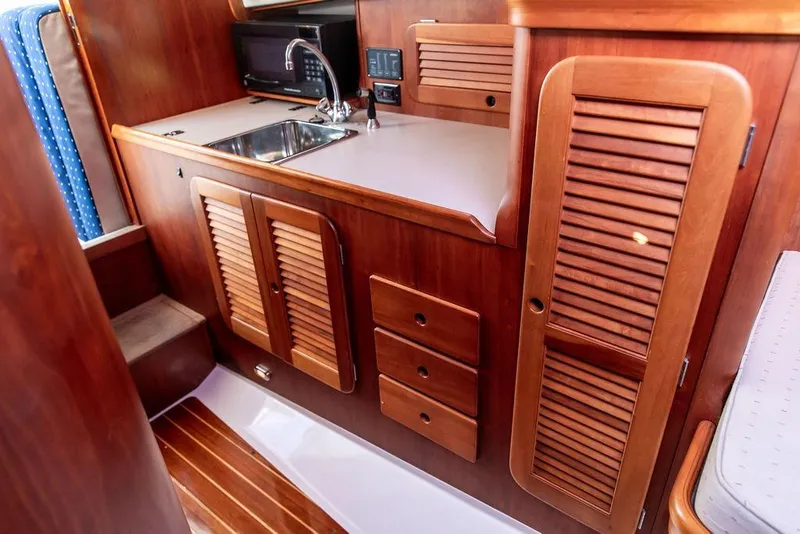 Slide: The Image of 2004 Hinckley Picnic Boat EP interior with wooden cabinetry and compact kitchen area. - 19