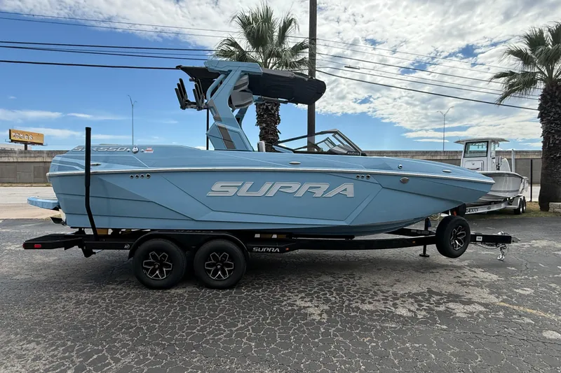The Image of 2026 Supa SA 550 boat on trailer, parked outdoors with palm trees and cloudy sky. - 0