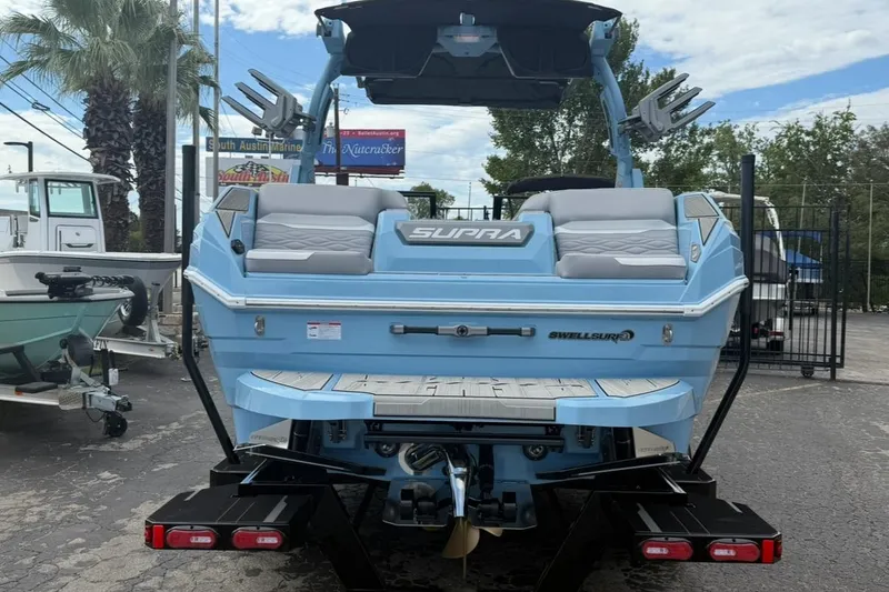 Slide: The Image of 2026 Supra SA 550 boat, blue exterior, rear view, parked at marina. - 4
