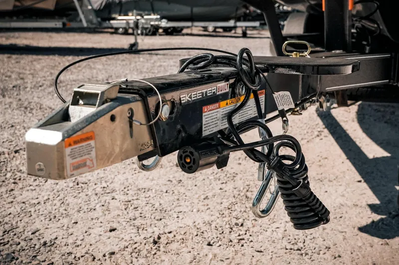 Slide: The Image of 2024 Skeeter ZX200 trailer hitch with safety cables and warning labels. - 23