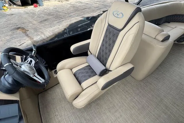 Slide: The Image of 2023 Harris Sunliner 250 boat interior with beige and gray captain's chair and steering wheel. - 13