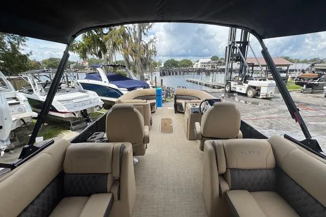 Slide: The Image of 2023 Harris Sunliner 250 pontoon boat interior with beige seating, docked at marina. - 19