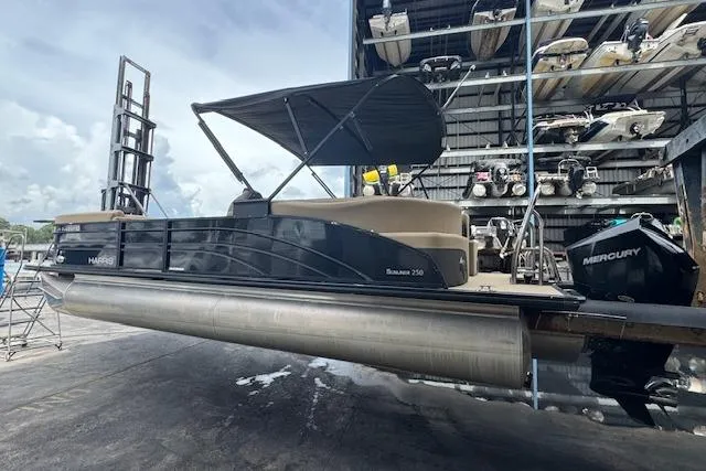 Slide: The Image of 2023 Harris Sunliner 250 pontoon boat with Mercury engine in storage facility. - 6