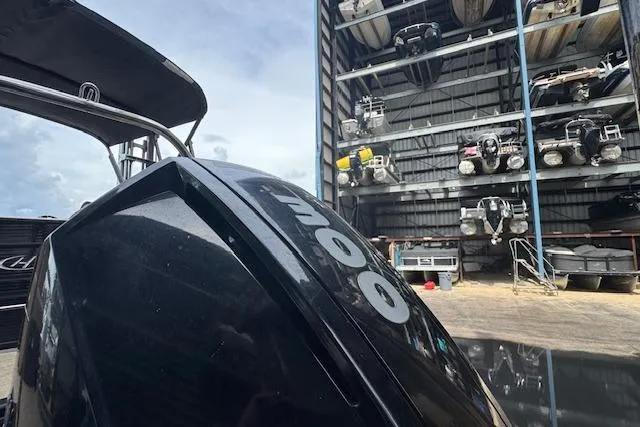 Slide: The Image of 2023 Harris Sunliner 250 boat in storage facility with multiple boats stacked on racks. - 8