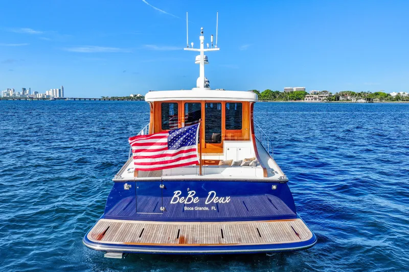 Slide: The Image of 2023 Vicem 65 Classic yacht on water, American flag, city skyline in background. - 5