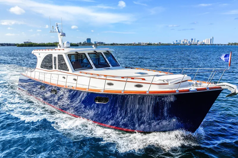 Slide: The Image of 2023 Vicem 65 Classic yacht cruising on blue ocean with city skyline in background. - 8