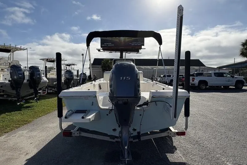 Slide: The Image of 2025 Bulls Bay 2000 boat with 115 HP engine, parked outdoors under a cloudy sky. - 2