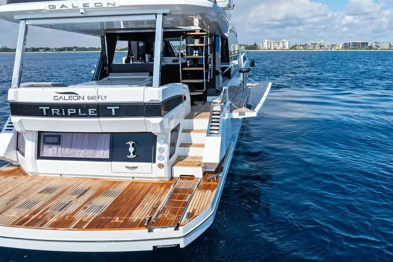 Slide: The Image of 2022 Galeon 640 Fly yacht on water, rear view with open deck and city skyline. - 10