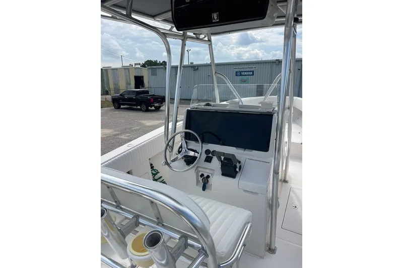 Slide: The Image of 2003 Jupiter 27 boat cockpit with steering wheel and controls, parked near industrial buildings. - 22