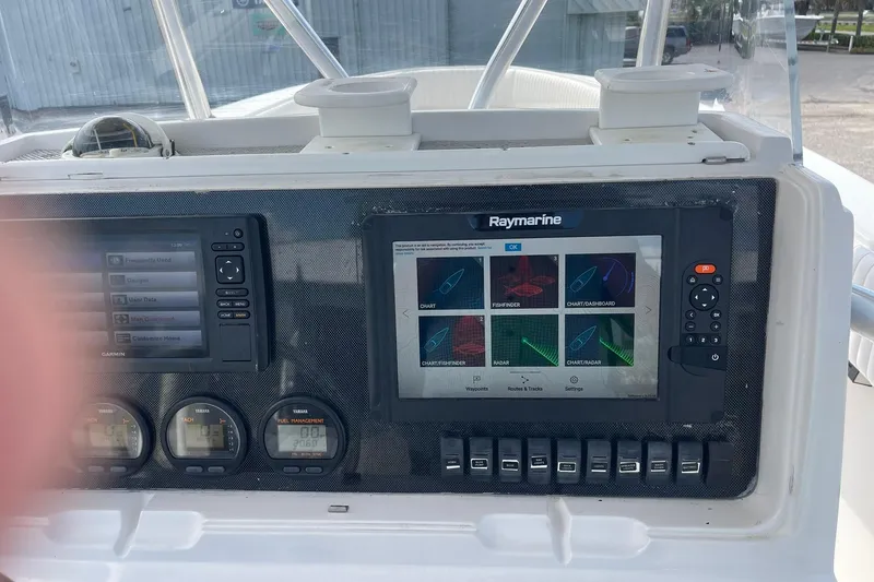 Slide: The Image of Boat dashboard with Garmin and Raymarine displays, steering wheel, and controls. Jupiter 27, 2003 model. - 26