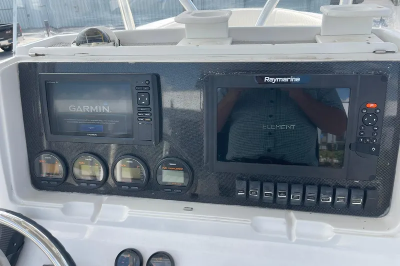 Slide: The Image of Boat dashboard with Garmin and Raymarine displays, Yamaha gauges, and switches. Jupiter 27, 2003 model. - 29