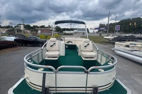 Slide: The Image of 2005 Tahoe Fish-N-Fun 22 pontoon boat with green deck, parked outdoors under cloudy skies. - 6