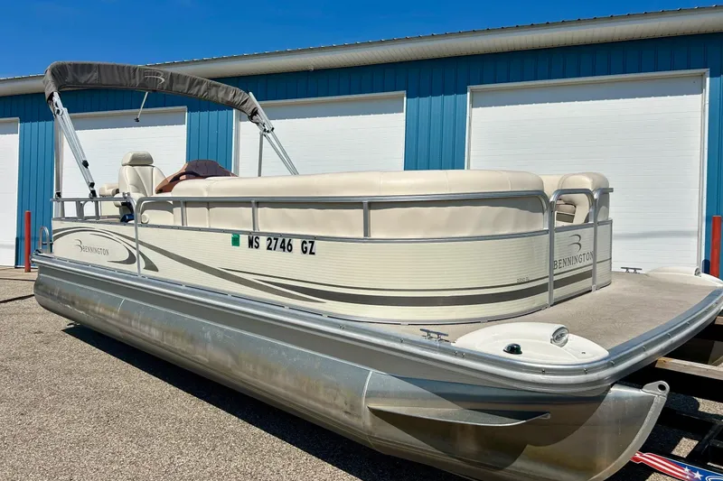 Slide: The Image of 2006 Bennington 2250 RL pontoon boat parked near blue building. - 2