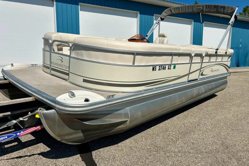Slide: The Image of 2006 Bennington 2250 RL pontoon boat parked on a trailer near blue storage units. - 41