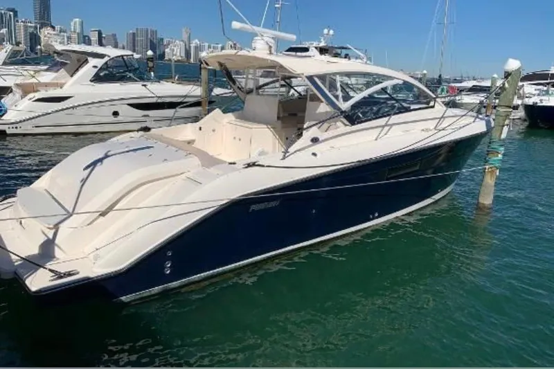 Slide: The Image of 2014 Pursuit SC 365i Sport Coupe docked in a marina with city skyline. - 2