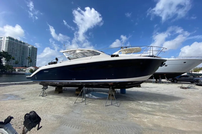 Slide: The Image of 2014 Pursuit SC 365i Sport Coupe yacht on dry dock under a clear blue sky. - 26