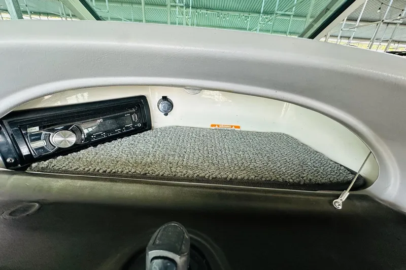 Slide: The Image of 2005 Chaparral 220 SSi boat interior with JVC stereo system and carpeted storage area. - 23